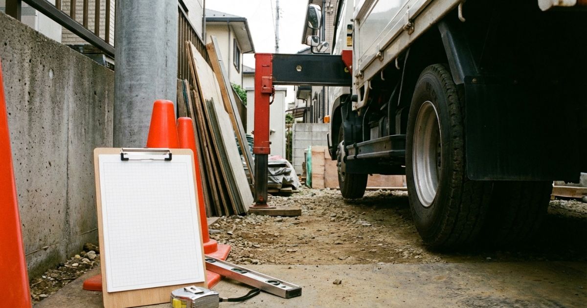 2tユニックが狭い現場で性能表を確認しながら作業準備するイメージ