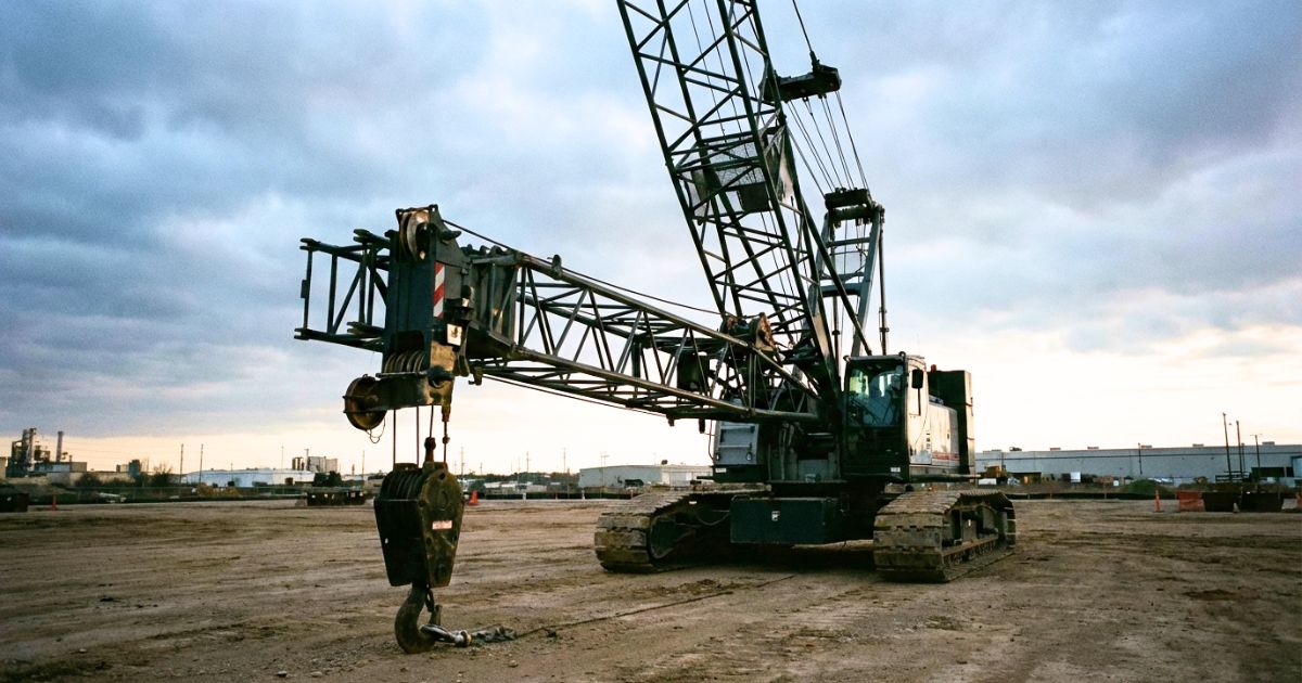 吊り荷なしで安全姿勢のクローラークレーンが作業ヤードに待機する操作イメージ写真