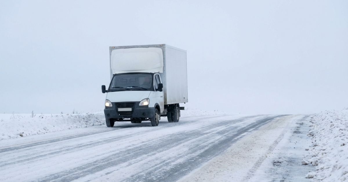 雪道を走る業務用トラックの実在感と冬季運行の雰囲気が伝わる写真イメージ